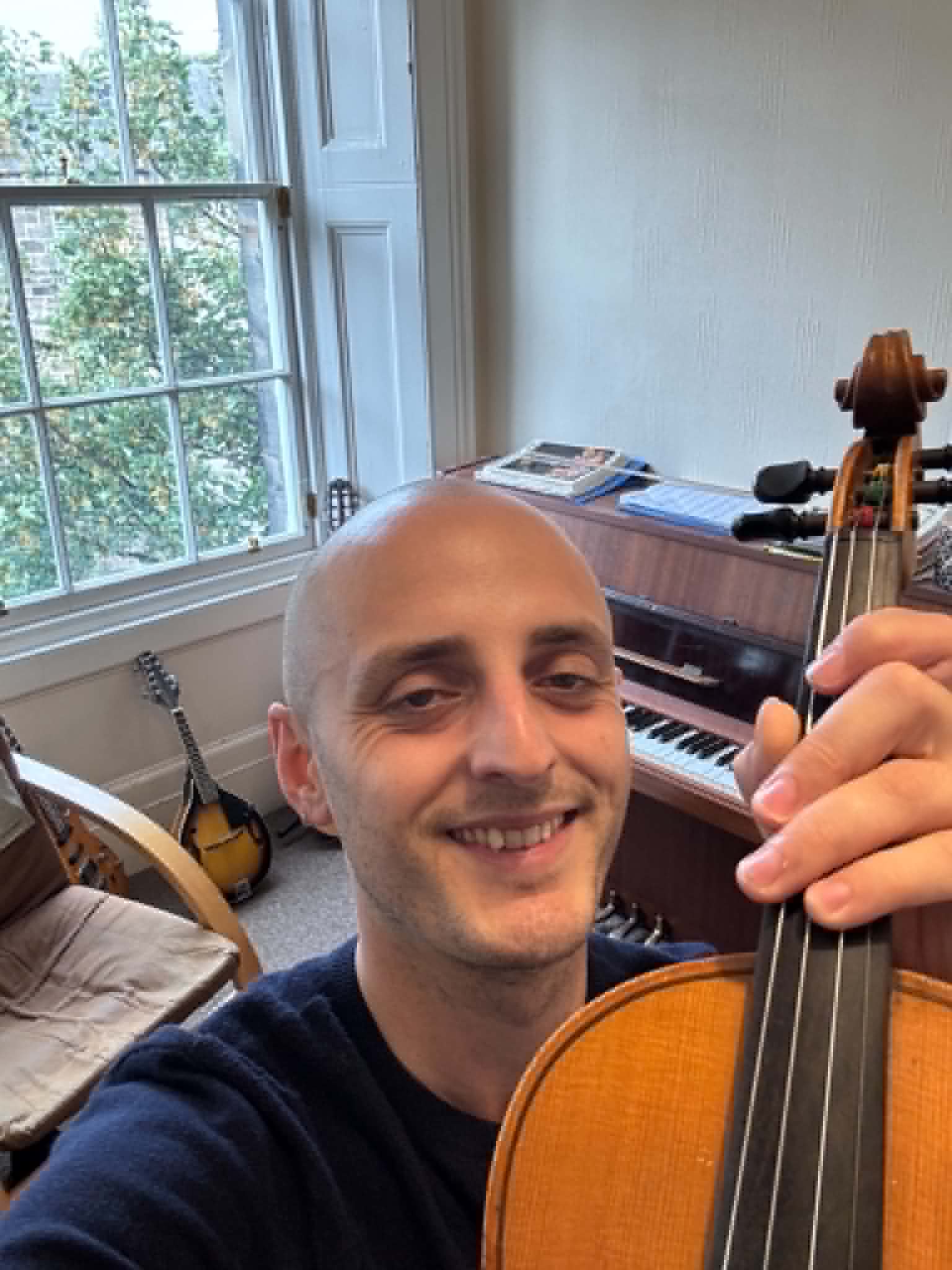 Ed White smiling with his violin in his teaching room
